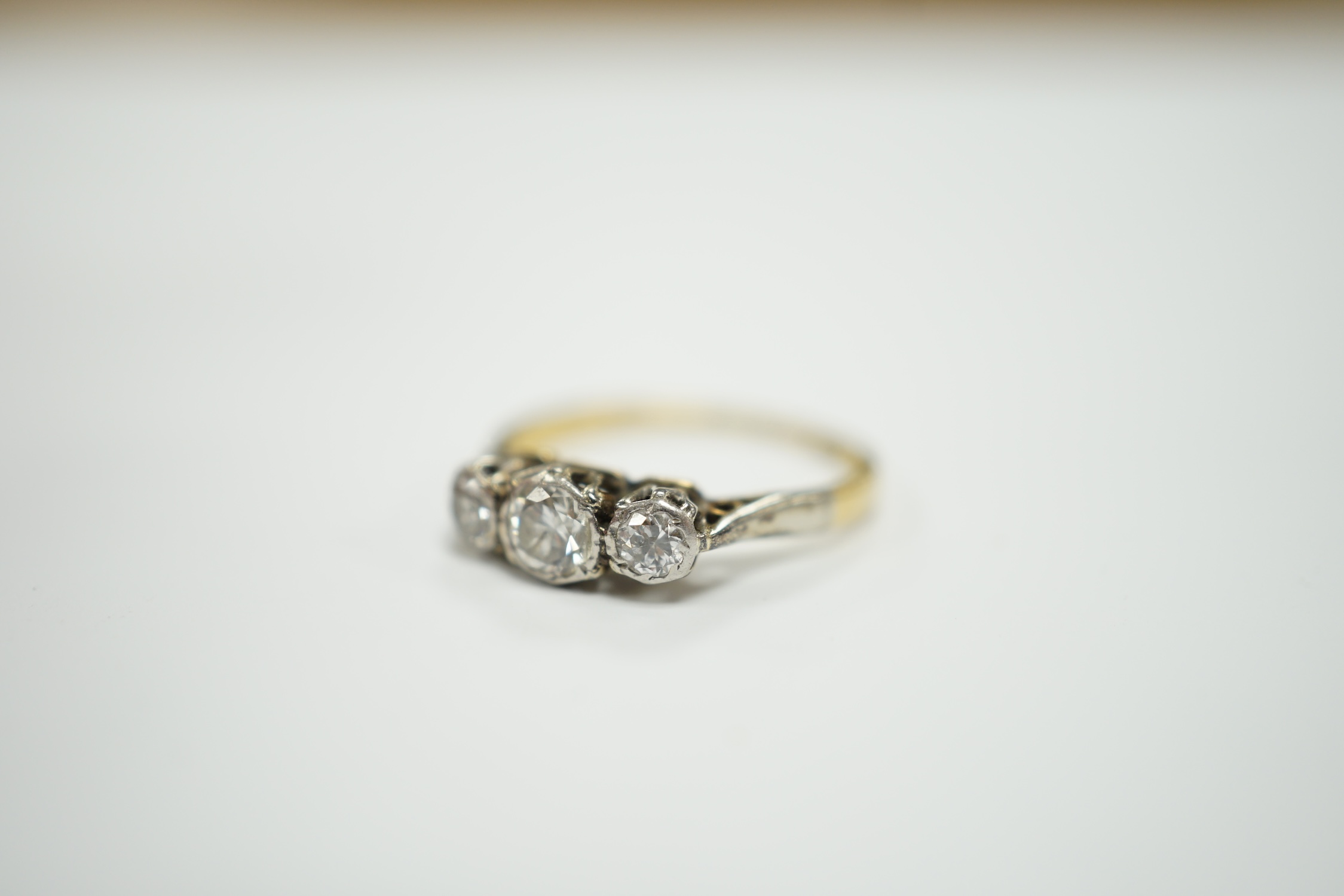 An 18ct and illusion set three stone diamond ring, size I, gross weight 2 grams.